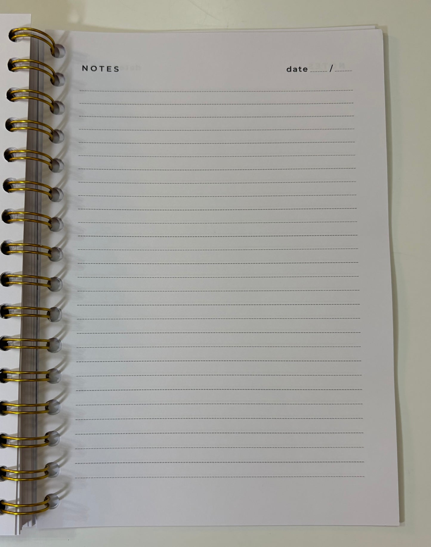 Notebook with lined pages and gold spiral binding on a white background