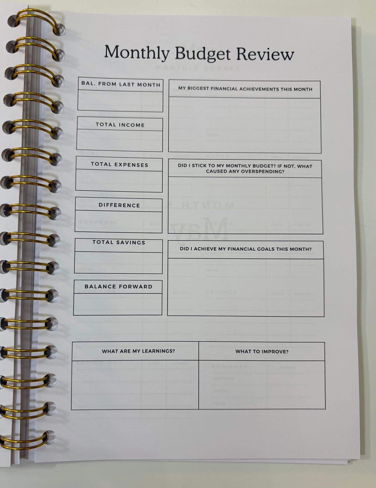 Monthly Budget Review worksheet in a spiral-bound notebook on a white background