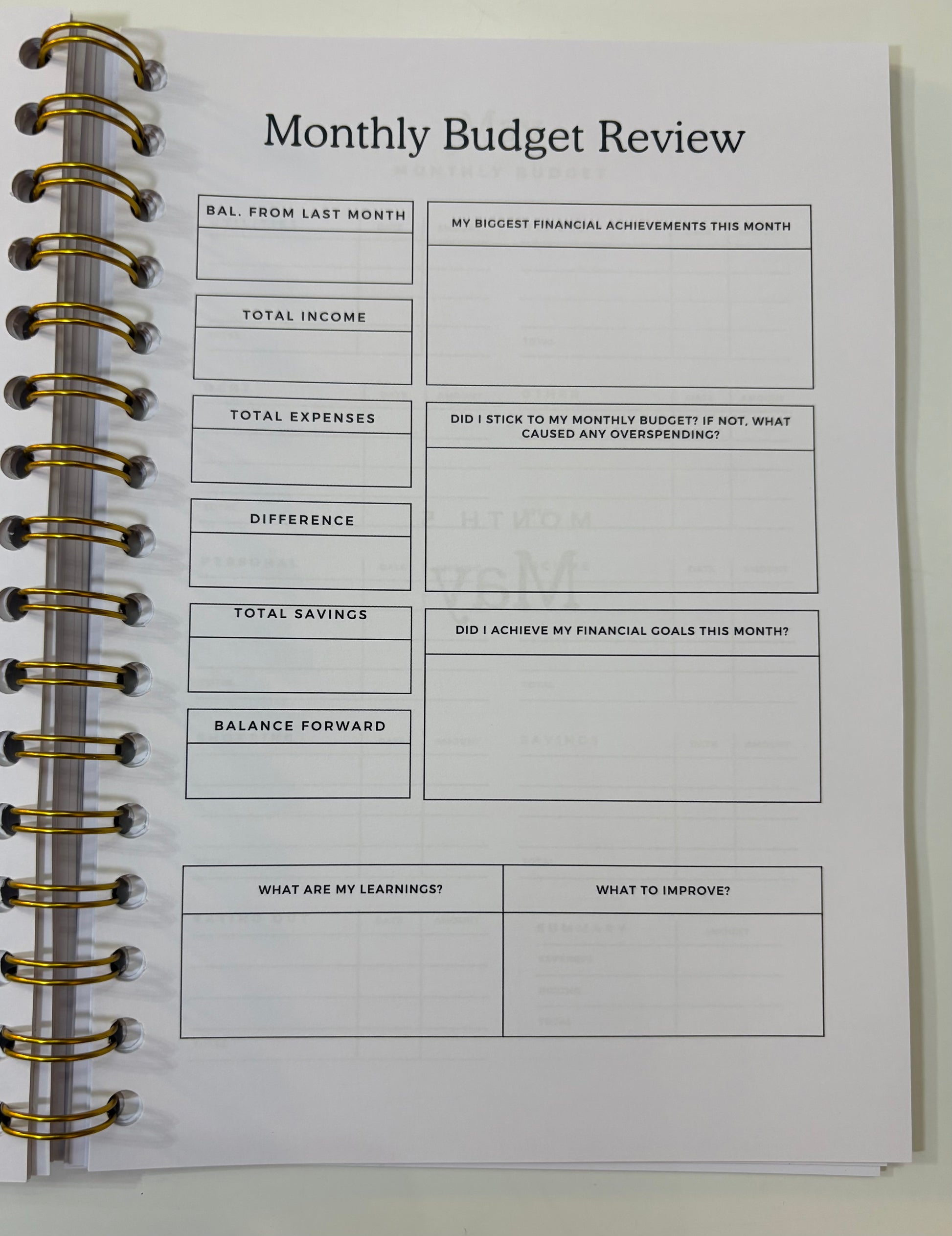 Monthly Budget Review worksheet in a spiral-bound notebook on a white background